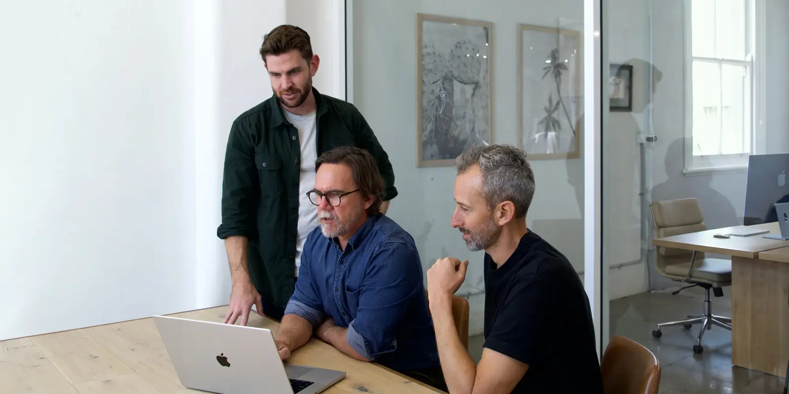 The three founders of Outlign at the studio table, looking at a laptop together